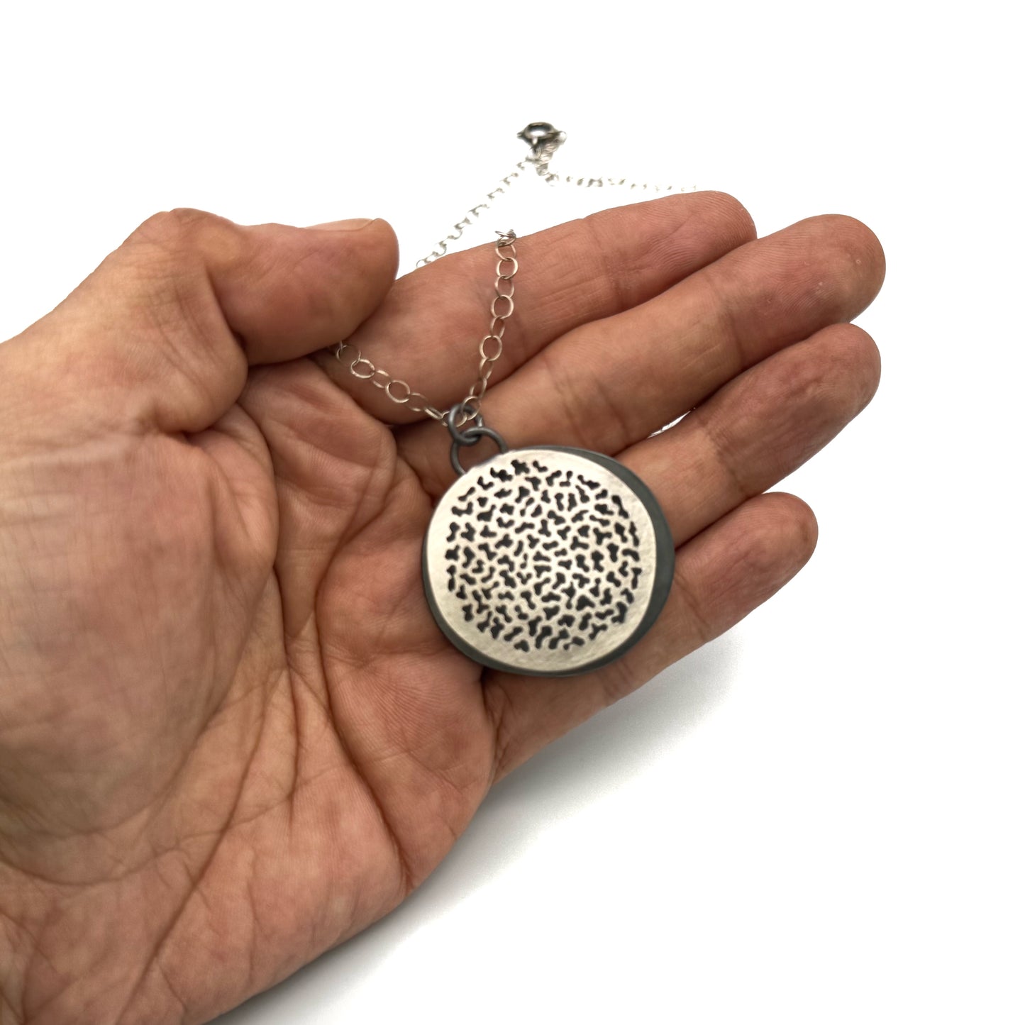 Hand pierced oxidize, silver pendant.